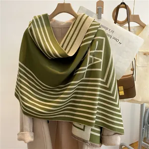 Détail d'une écharpe en cachemire à rayures vert foncé et beige avec franges élégantes