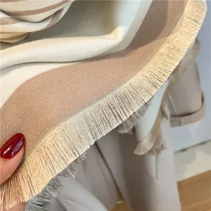 Close-up of fringe details and soft striped knit texture on a cozy cashmere-style shawl