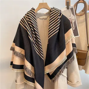 Detail of striped cashmere-like shawl with fringes hanging on a wooden hanger