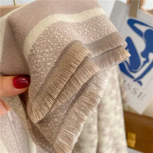 Close-up of thick beige and light coffee star scarf with fine fringe details