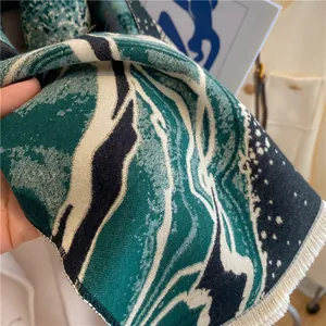 Dettaglio di sciarpa in maglia verde con motivo jacquard astratto e frange sottili