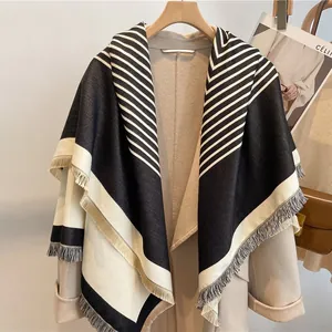 Thick black and white striped cashmere-like shawl with tassels over a beige coat
