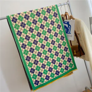 Détail d'écharpe à carreaux vert et bleu avec de longues franges jaunes sur cintre