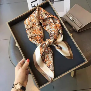 Orange and coffee silk scarf with H-pattern geometric design on a black display tray