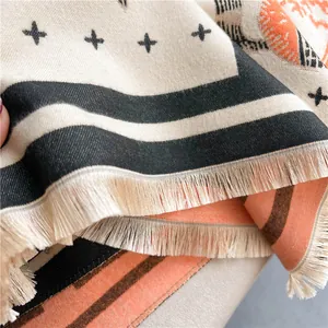 Detail of soft cashmere feel shawl featuring geometric patterns and delicate fringe