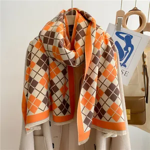 Détail d'une écharpe douce aspect cachemire à motif losanges orange et beige avec franges