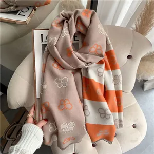 Detail of butterfly pattern scarf with fringe edges and warm orange and brown tones