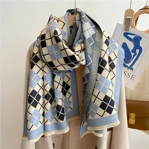 Détail d'une écharpe à losanges bleus en cachemire avec franges sur un manteau beige