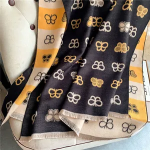 Detail of butterfly pattern jacquard scarf with tassels on a beige sofa chair
