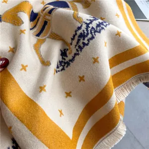 Detailed close-up of thick cashmere scarf featuring horse motifs and soft beige tassels