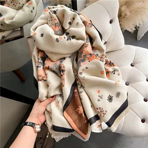 Close-up of soft cashmere-like beige scarf with elegant floral patterns and fringe