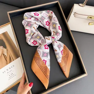 Silk twilly scarf in white and orange with floral patterns wrapped for bag handle