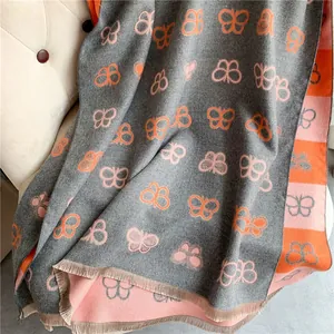 Detail of gray cashmere-like scarf with butterfly pattern and fine tassel edges