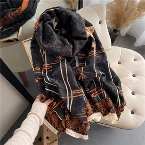 Detailed texture of thick cashmere-like scarf with orange vintage patterns and beige tassels
