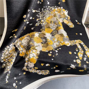 Macro detail of the black cashmere-feel scarf showing floral horse pattern and fine tassels
