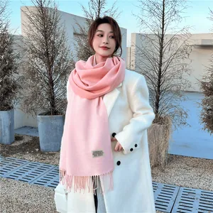 Bufanda rosa de cachemira con flecos y etiqueta usada con un abrigo blanco exterior