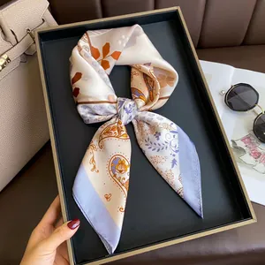 Satin silk scarf featuring orange paisley patterns on a luxury cream background