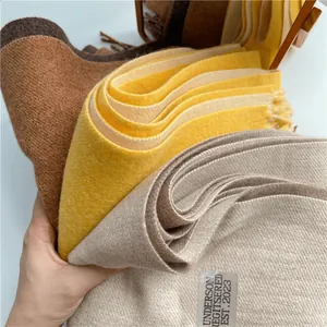 Primer plano de bufandas de pashmina gruesa en colores marrón, amarillo y gris con flecos