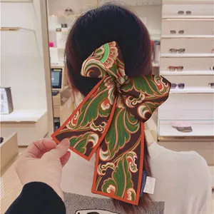 Close-up of retro baroque print silk scarf tied as a hair ribbon on a person