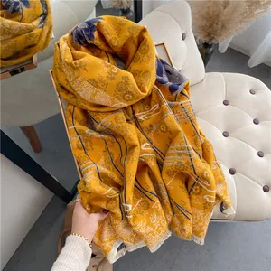 Detail of ginger yellow cashmere shawl with blue floral patterns and soft fringe edges