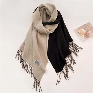 Detalle de una bufanda de punto suave con flecos y un diseño bicolor en negro y beige