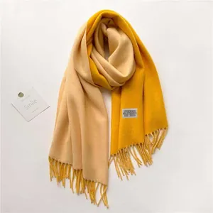 Detalle de bufanda de cachemira bicolor amarillo y beige con flecos y etiqueta