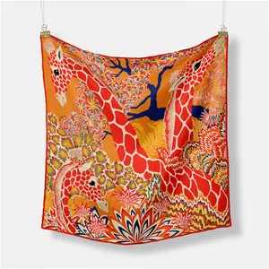 Dettaglio di un foulard in seta con giraffe arancioni e motivi floreali vivaci