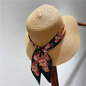 Detail of a straw sun hat with floral ribbon tie on a vintage wooden stand