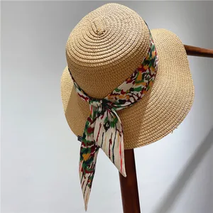 Detail of a flat top straw sun hat with vibrant abstract print ribbon tied in a side bow