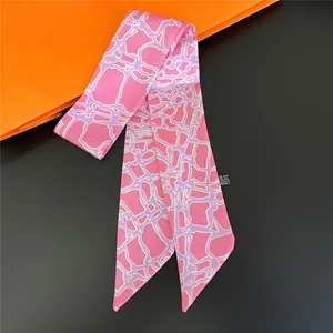 Pink narrow long silk scarf with purple geometric print displayed on orange background