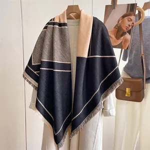 Détail d'un châle bicolore à franges avec panneaux beiges et gris sur un manteau