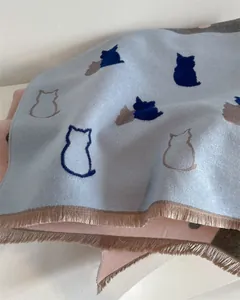 Close-up of cashmere scarf showing cat patterns and soft tassels in light blue