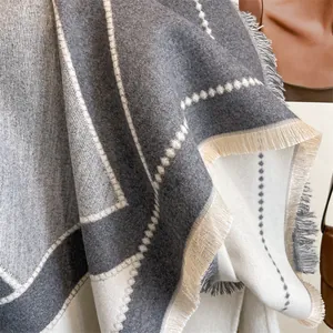 Détail d'une écharpe douce à motifs géométriques gris et beige avec bords à glands