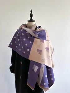 Detail of cashmere scarf featuring cat silhouette patterns, polka dots and fringe trim
