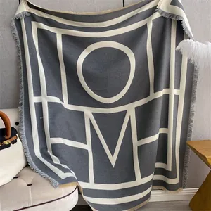 Detailed view of heavy knit throw blanket with HOME jacquard pattern and fringe edges