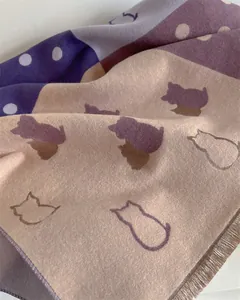 Close-up of thick cashmere scarf with purple geometric cat patterns and white polka dots