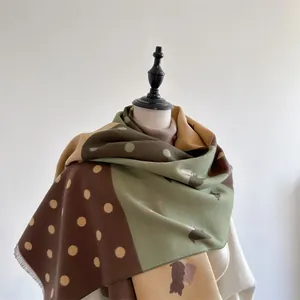 Detail of color-block cashmere scarf with polka dots and frayed fringe edges in earth tones