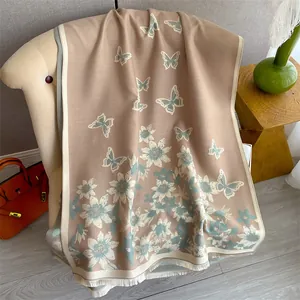 Detail of beige cashmere-feel scarf with blue butterfly print and soft fringe edges