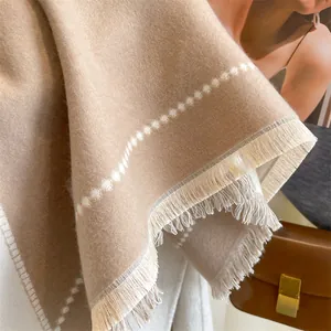 Gros plan d'un châle beige toucher cachemire avec motifs à pois et détails de franges