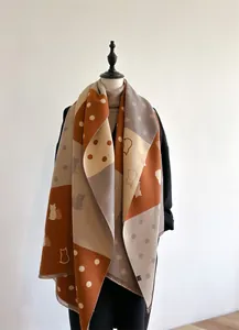 Close-up of caramel and grey patchwork cashmere scarf featuring cat silhouettes and polka dots