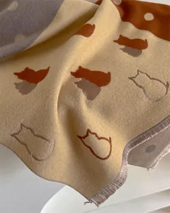 Detail of cashmere scarf showing cat silhouette patterns and soft fringe edges