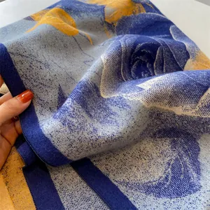 Detail eines weichen dicken Schals mit großem blau-gelbem floralem Rosenprint-Muster