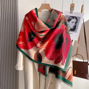 Detail of floral cashmere shawl with red poppy print and tassel trim on beige coat