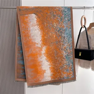 Close-up of colorful thick pashmina scarf with orange and blue abstract ink pattern and fringe