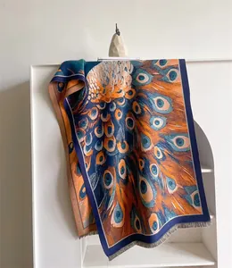Détail du motif de plumes de paon sur un châle d'hiver épais avec des bords à franges