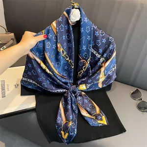 Macro detail of dark blue floral print silk scarf featuring golden chain patterns