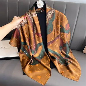 Macro detail of caramel brown silk scarf showing chain patterns and rolled edges
