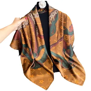 Caramel brown silk scarf with chain print displayed on mannequin with camellia