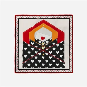 Close-up detail of a 53cm square scarf featuring envelope and heart prints in red and orange