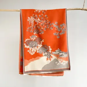 Detailed view of orange cashmere-like scarf with Chinese floral patterns and fringe